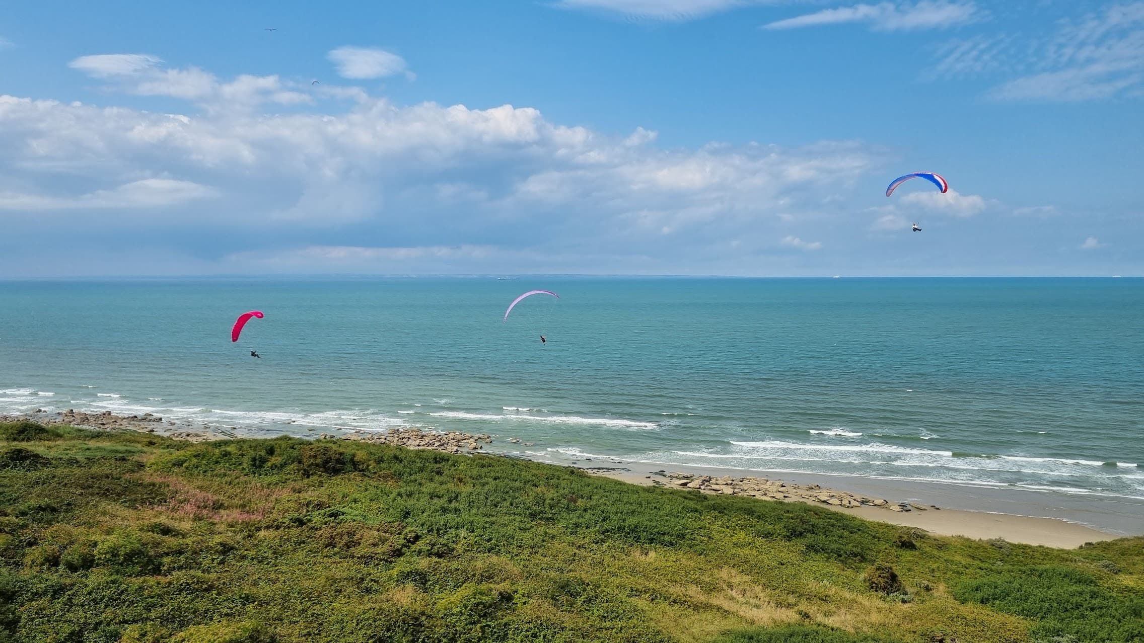 Paragliders die soaren boven de duinen langs de kust